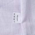 Makroaufnahme der lavendelfarbenen Baumwollkleid-Textur und des 100% Baumwolle-Etiketts - Lavendel