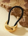 Detail einer halbmondförmigen goldenen Haarspange mit schwarzem Haargummi auf einem Stein - Mondsichel Gold