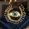 Detailed close-up of golden evil eye brooch with blue iris and sparkling crystals - Eye Series-1
