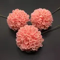 Three pink artificial dahlia flowers with green stems on dark grey textured background - Nude Pink