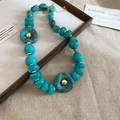 Detailed close-up of acrylic turquoise necklace with gold accents on rustic linen - Necklace-Green