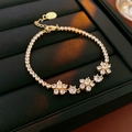 Close-up of gold flower bracelet with sparkling zircons on black jewelry tray - Clear Zirconia / Gold