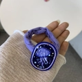 Detail of purple fabric hair tie featuring a dark blue jellyfish charm held by hand - Deep Sea Blue Jellyfish