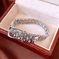 Gros plan du bracelet boucle de ceinture argenté avec zircons blancs sur satin rouge - Style Boucle de Ceinture / Argent