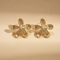Macro detail of golden flower stud earrings with brushed texture and center beads - Gold