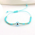 Detail of adjustable blue devil eye beaded bracelet with gold accents on white base - Type H-Blue Evil Eye