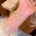 Elegantes Goldarmband mit Schmetterlingen, Zirkonia und Perlmutt am Handgelenk einer Frau - S772 Gold