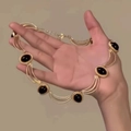 Gros plan d'un collier vintage doré à trois rangs serti de pierres ovales noires - Or-Ovale
