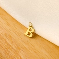 Detailed view of a golden letter B pendant on a rustic wood and linen surface - 14k Letter - B (letter Height 1cm)