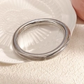 Détail d'un bracelet serpent argenté sur une assiette en céramique blanche gaufrée et tissu - Bracelet manchette ouvert serpent à ressort argenté