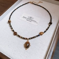 Close-up of tiger eye stone pendant and colorful beads on a jewelry display tray - Titanium Steel Water Drop Tiger Eye Rice Bead Necklace