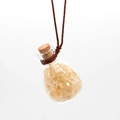 Detailed macro view of a clear glass perfume bottle pendant with yellow crystal stones - Citrine