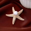 Dettaglio macro della spilla a stella marina placcata oro 14K con perla e zirconi - Oro