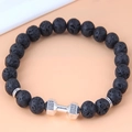 Macro shot of black lava rock beads and silver dumbbell charm with Live Lift engraving - Dumbbell Live Lift