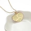 Elegante gouden roestvrijstalen hart hanger ketting op een decoratieve keramische schaal - Gouden Hart Ketting