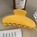 Close-up of a large yellow acetate hair claw clip on a decorative ceramic plate - 10cm / Yellow