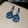 Dettaglio macro di orecchini a forma di pipa con rose blu, strass e smalto stile vintage - ago in argento - blu
