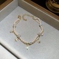 Detalle de la pulsera de doble capa con perlas blancas y colgante de estrella dorada - Dorado