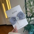 Détail d'une pince à cheveux nœud en tissu bleu clair sur carte de présentation - Muguet - Nœud Bleu Brume Pince à Bec de Canard