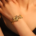 Adjustable golden flower cuff bracelet featuring detailed petal engravings on model - Floral Relief