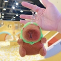 Brown capybara plush keychain with green hood accessory on a silver metal ring - Frog Hat Dark Brown + Silver Clip