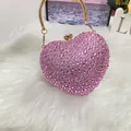 Close-up of pink rhinestone heart-shaped evening bag with golden ring handle and clasp - Pink