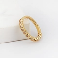 Anillo clicker dorado con circonitas engastadas sobre soporte de mármol blanco - Circón Redondo Blanco