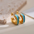 Detailaufnahme goldener C-förmiger Creolen mit himmelblauer Emaille auf Steinhintergrund - Blau