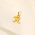 Detailed view of a gold-plated stainless steel letter R pendant on beige fabric - Letter-R