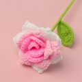 Handgehäkelte Rosenblüte in Rosa und Weiß mit grünem Stiel auf rosa Hintergrund - Glitzer mit Farbverlauf