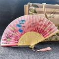Pink folding fan with cherry blossoms and tassels on dark textured background - Ten Miles of Peach Blossoms - Pink