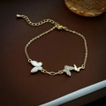 Detailed close-up of gold-plated butterfly bracelet with zircon and shell pendants - Gold