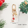 Christmas snowman keychain with gold ring and pearl charm against pine branches - Drumming Snowman