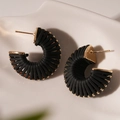 Nahaufnahme von schwarzen geflochtenen Kunstleder-Creolen mit goldenen Metalldetails - Stahlstift - Schwarz Leder Gewinde Ohrstecker