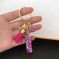 Detailed view of pink resin letter keychain with golden ring and sparkling star sequins - Small Ball Tassel Clasp / Letter I