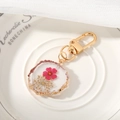 Detalle de llavero de resina artesanal con flores secas y detalles de pan de oro - Flor Blanca Rojo Rosa