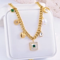 Collar bohemio dorado con colgante de esmeralda y dijes mixtos sobre un joyero blanco - Cuadrado de Zirconia