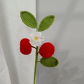 Macro shot of handmade crochet strawberry branch with white flowers and green leaves - Apple