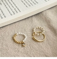Dettaglio di anelli dorati con perle e zirconi su lino rustico e pagine di libro vintage - Set da tre pezzi in oro (placcato in oro vero)