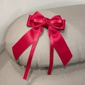 Elegant red satin bow hair clip with long ribbons shown on a gray textured background - Red