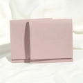 Detail of two pink PU leather drawstring pouches with embossed logo on soft white cloth - Light Purple