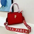 Detalle de bolso de cuero rojo con logo P dorado y correa ancha de tela estampada - Rojo