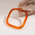 Macro detail of amber resin bangle showing fluid texture on textured stone base - Translucent Square Amber Style