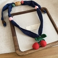 Close-up of handmade crochet red cherry pendant with wooden beads on navy fabric cord - Blue (Crochet Cherry Style)