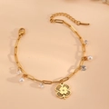 Pulsera de acero inoxidable dorada con trébol, perlas y cristales sobre fondo color crema - Pulsera de Perlas de Trébol Dorado (F312)