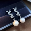 Detail view of pearl earrings with Y-shaped logo and rhinestones on blue velvet - Silver Letter Style