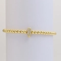 Macro shot of gold beaded bracelet with a zircon-encrusted oval pendant on a white stand - Letter I