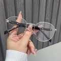 Detail of silver round metal frames with black temples held against a grey wall - Silver Frame Clear Lens