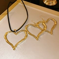 Golden heart-shaped zircon necklace and earrings set on a beige display tray - Hollow Heart Black Cord Design / Gold