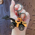 Miniatuur gele bulldozer sleutelhanger met metalen clip in de hand voor schaal - Gele sloopmachine